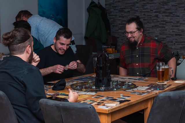 A group laughing around a table with a game in progress